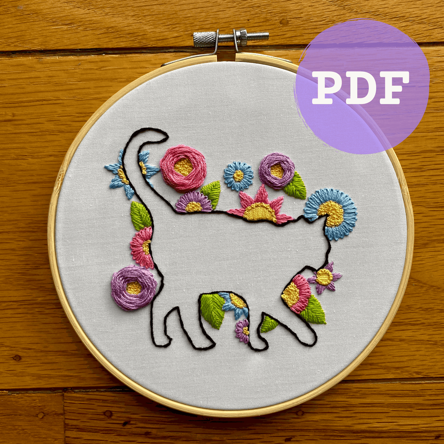 Cat silhouette surrounded by colorful embroidered flowers in a digital PDF pattern.