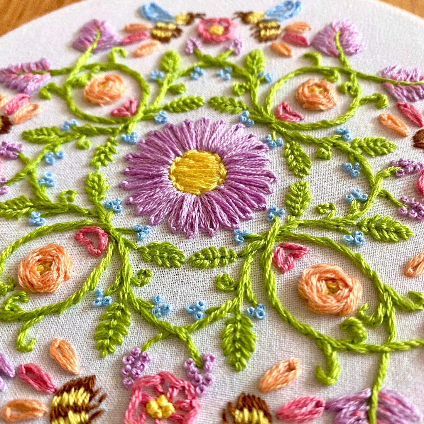 Pastel floral and honeybee mandala embroidery design in a 6-inch hoop.