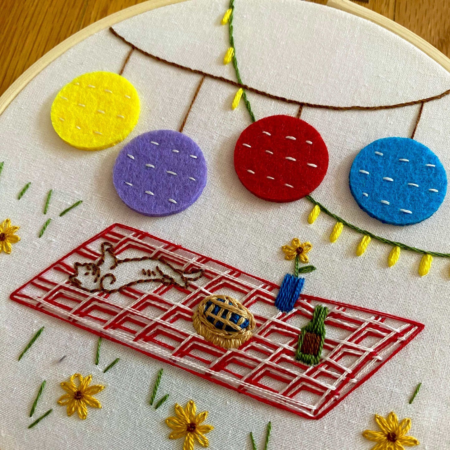 Picnic-themed embroidery kit with colorful felt lanterns and textured stitches in a hoop.