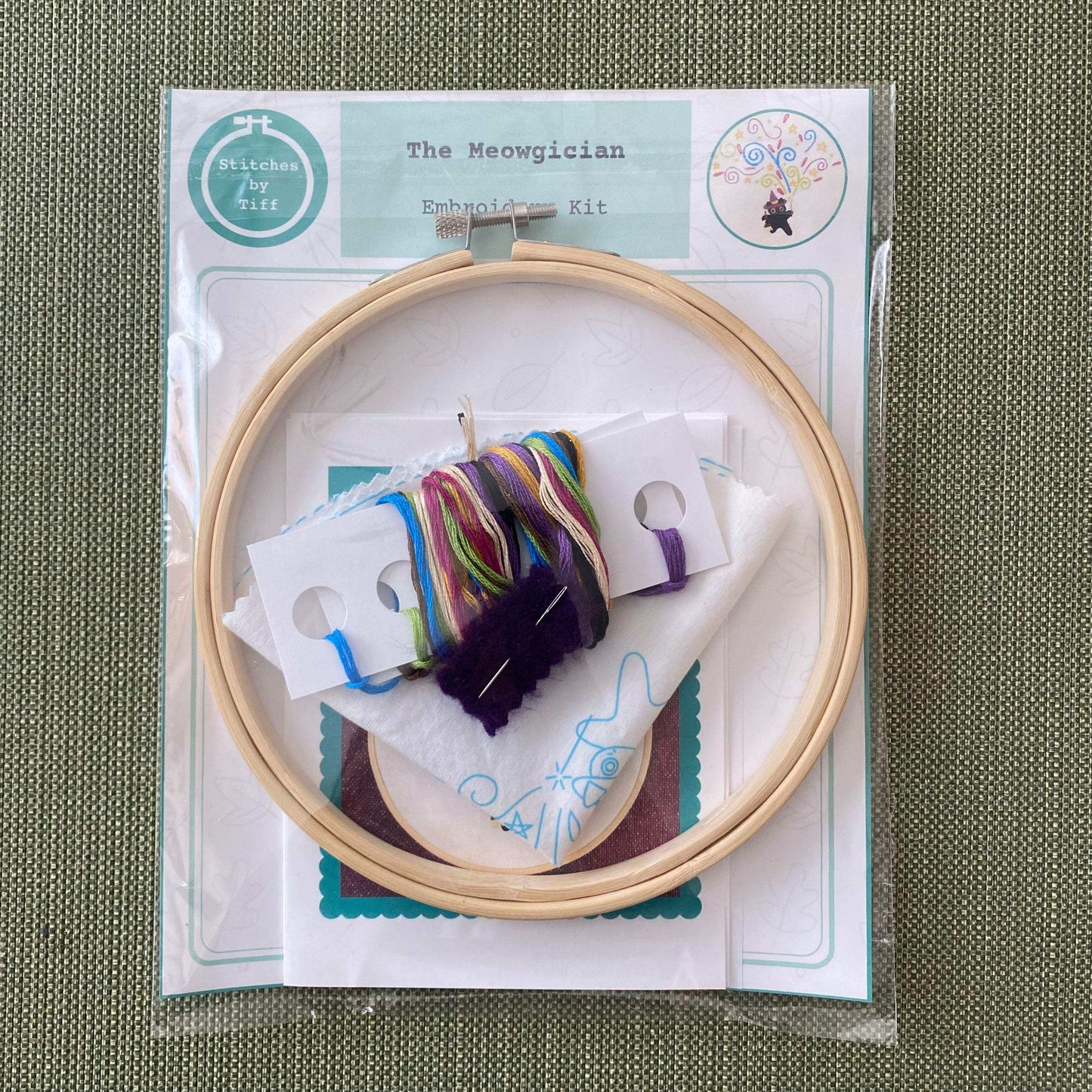 The Meowgician Embroidery Kit with hoop, pre-printed fabric, colorful threads, and instruction guide for beginner stitchers.