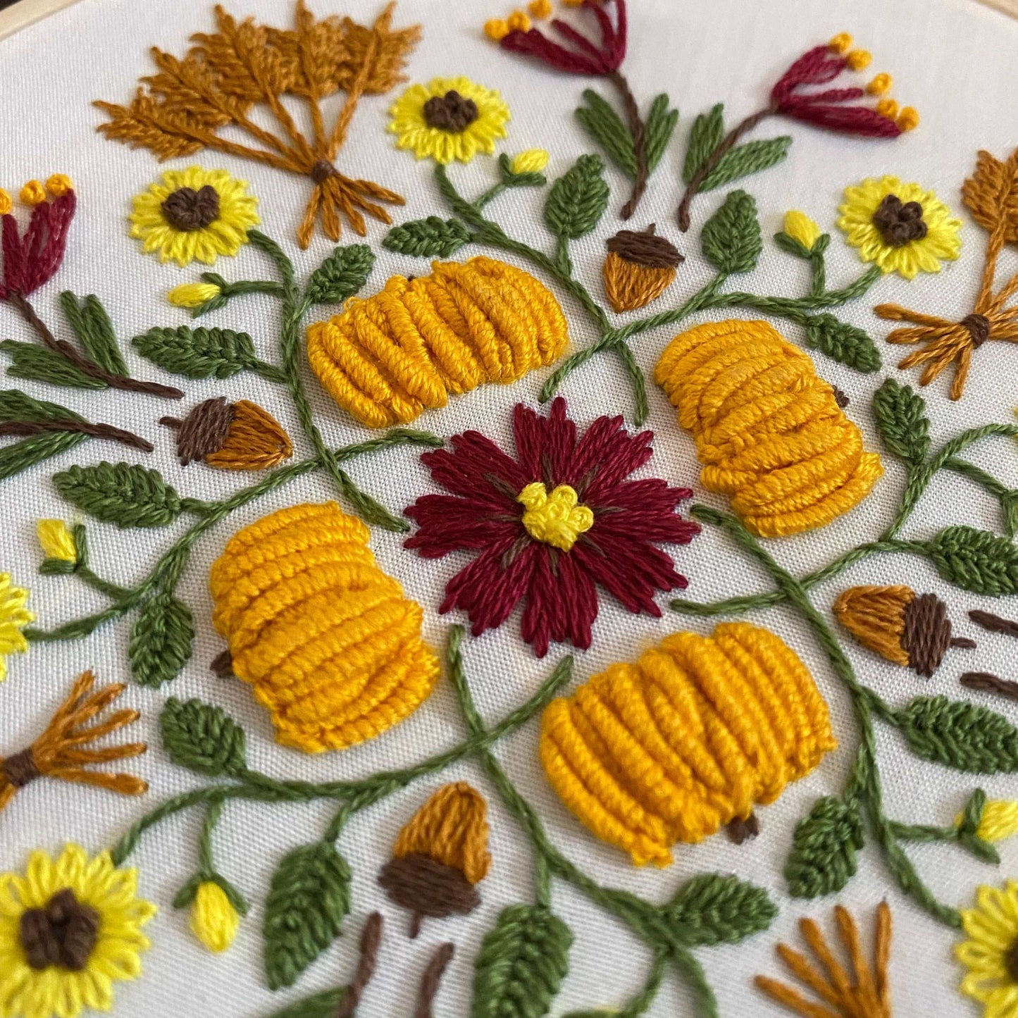 Autumn-themed mandala embroidery with pumpkins and flowers in warm colors.