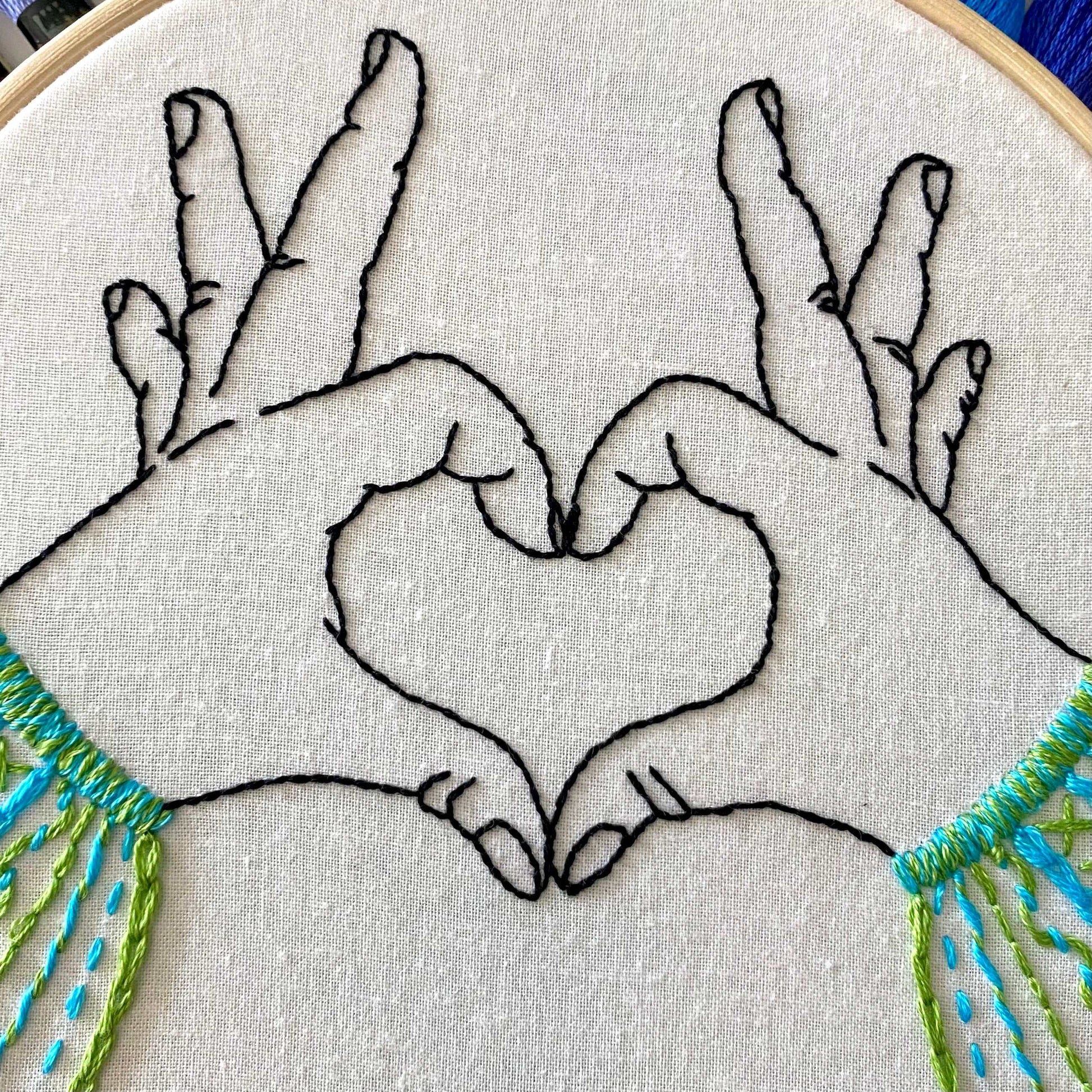 Heart hands embroidery pattern on fabric in bamboo hoop.