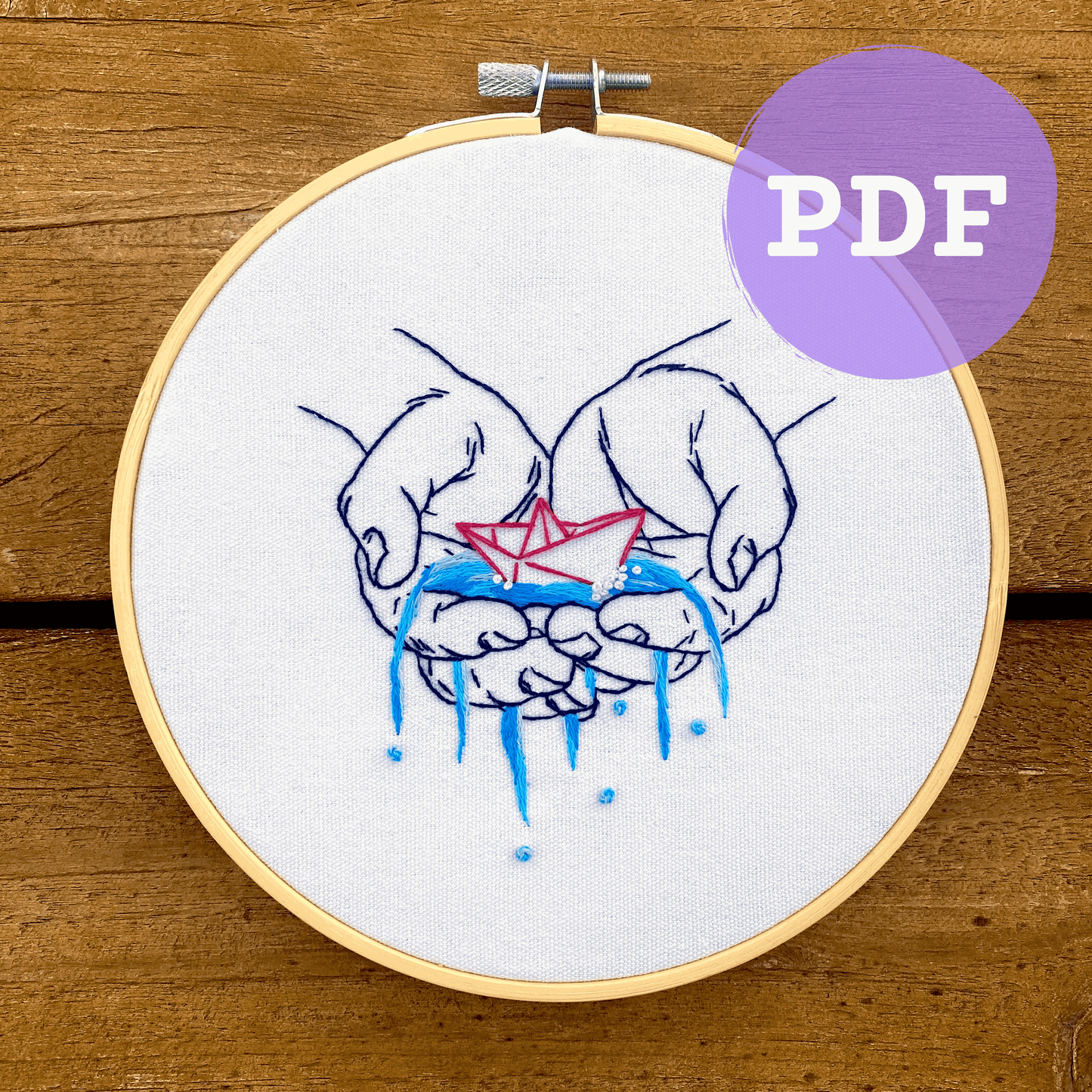Embroidery pattern PDF showing hands holding a paper boat, suitable for beginner and intermediate crafters.