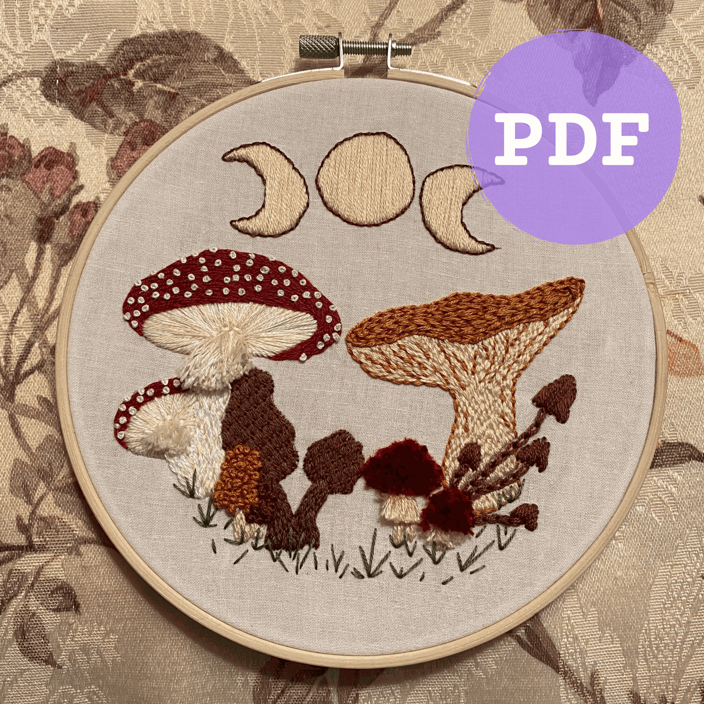 Embroidery hoop with mushroom pattern PDF design, featuring textured stitches and moon phases.