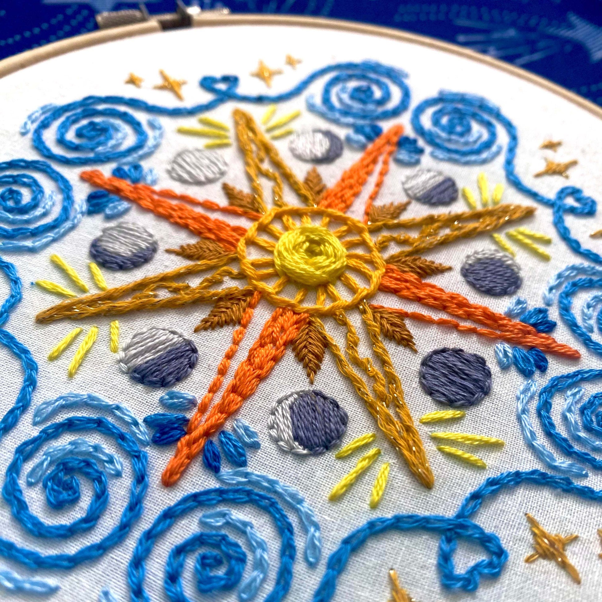 Celestial Mandala Sampler Embroidery Kit with sun, moon, and stars design in bold, sparkly colors on preprinted cotton fabric.